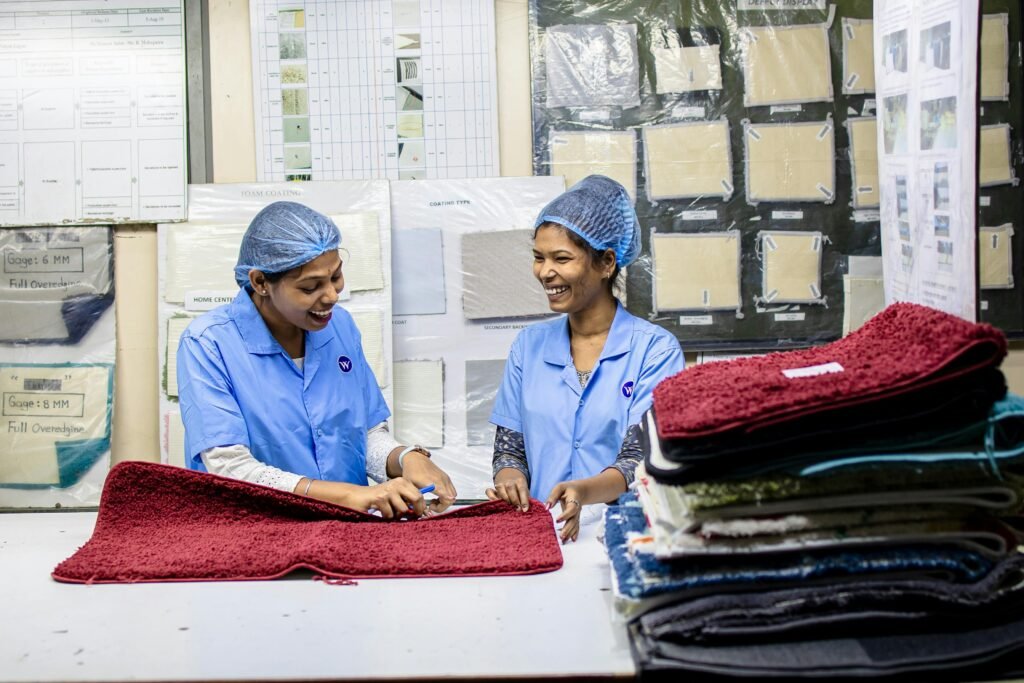 Two female textile workers in blue uniforms inspecting fabric in a factory.