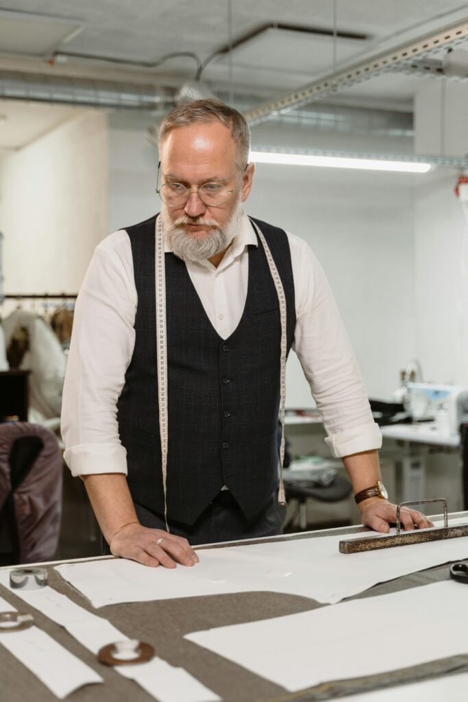 Senior tailor working with patterns in a modern clothing studio.
